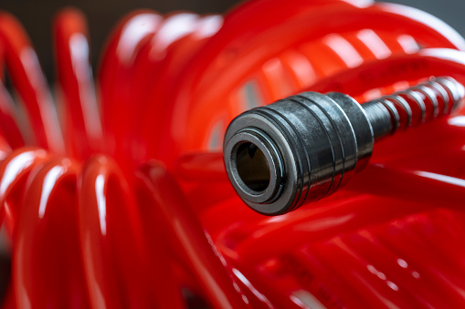 An orange air hose with an hose coupling , close up. Detail of air compressor hose and pistol