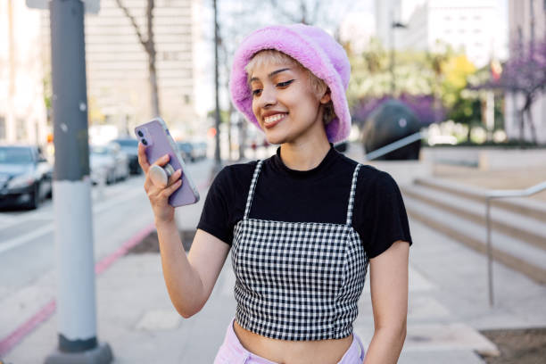 Portrait of a young woman with her mobile phone texting and scrolling social media in the streets Portrait of a young woman with her mobile phone texting and scrolling social media in the streets. alternative lifestyle stock pictures, royalty-free photos & images