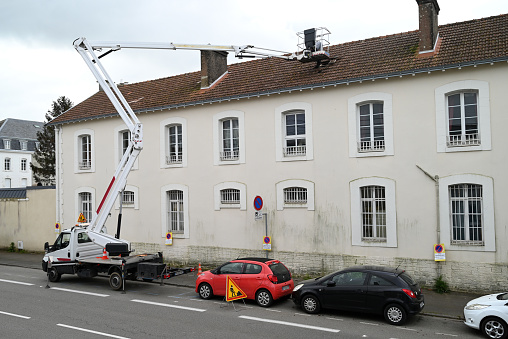 Vannes, France, april 15, 2024 : Telescopic bucket truck parked on a street working on a roofing site