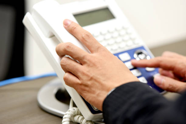 An Asian woman is distracted while using landline phone in the office