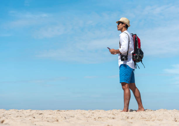 istock Relax asian man barefoot walking on tropical summer beach feeling fresh and freedom on holiday. Enjoyment barefoot walk outdoor with freedom. Relaxation Travel Concept. 2149938208
