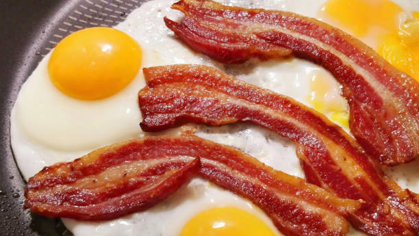 Freshly Fried Crunchy Gourmet Belly Bacon Bacon Rashers With Sunny Side Up Eggs Detail High Resolution Stock Image stock photo