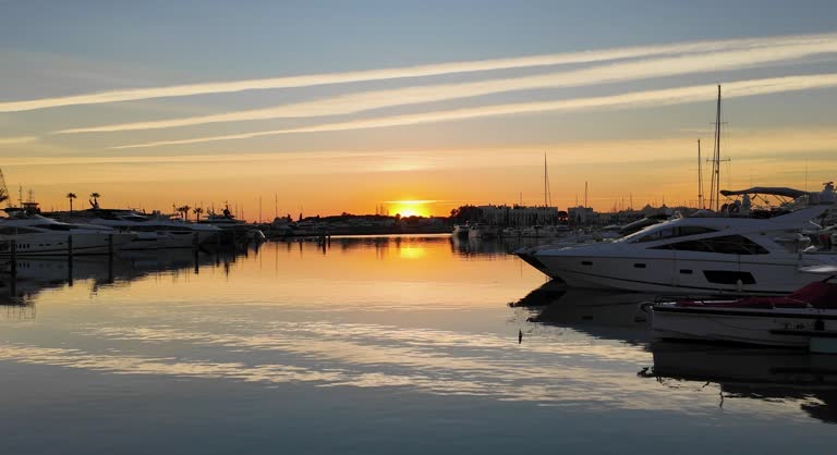 A 4K Static shot in Villamoura  of Chem trails reflected in the Marina water at sunset