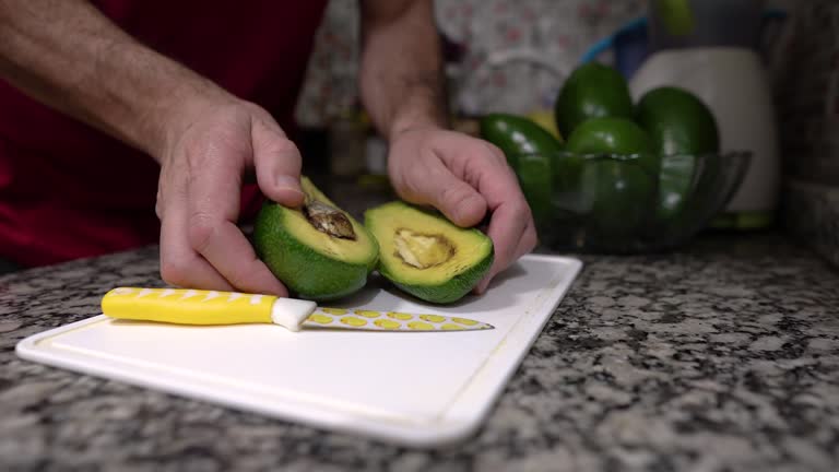 Healthy Cooking: Male Hands showing a Fresh Avocado in the kitchen. Copy space.