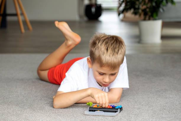 istock Focused boy deeply engaged in solving a colorful logic puzzle, enhancing his cognitive skills. 2149941805