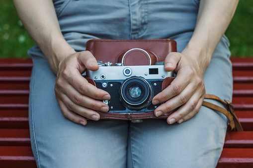 Girl with a vintage analog camera in her hands. Film camera. Closeup