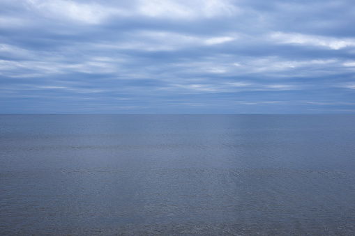 Tranquil blue ocean under a vast, overcast sky, conveying peace and solitude
