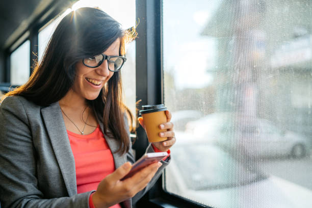 istock Young Woman Using Phone And Drinking Coffee To Go While Riding In A Bus 2149951332