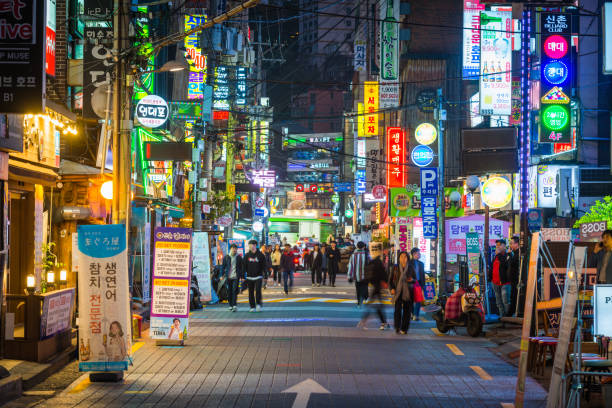 South Korea restaurants glowing neon night busy city streets Sinchon Seoul People walking through the neon lit night streets of Sinchon in the heart of Seoul, South Korea’s vibrant capital city. kangnamgu stock pictures, royalty-free photos & images