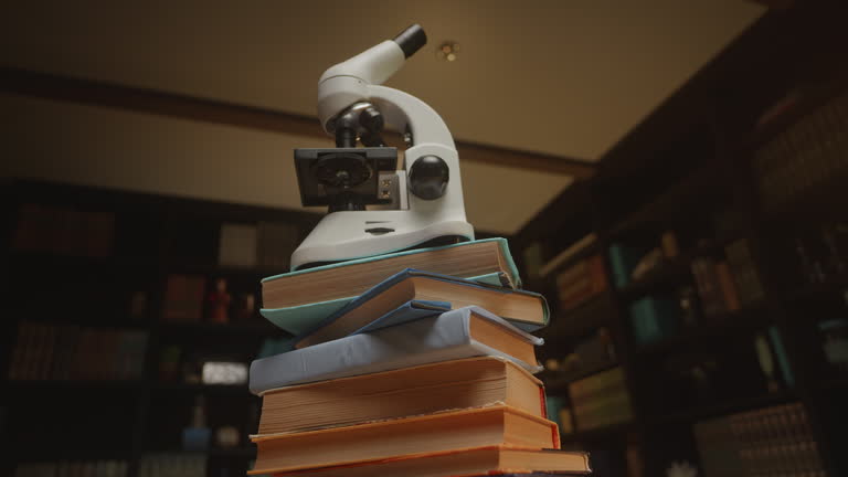 Bottom view on a microscope at the library on a stack of books, HQ 4K footage