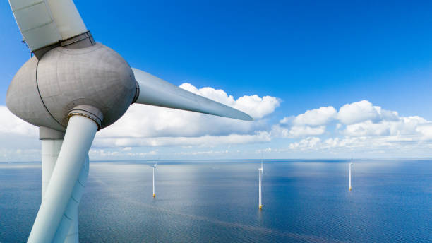 A mesmerizing aerial view of a wind farm in the ocean, with rows of windmill turbines gracefully spinning in the spring breeze, harnessing the power of the wind A mesmerizing aerial view of a wind farm in the ocean, with rows of windmill turbines gracefully spinning in the spring breeze, harnessing the power of the wind, green energy in the Netherlands offshore wind farm stock pictures, royalty-free photos & images