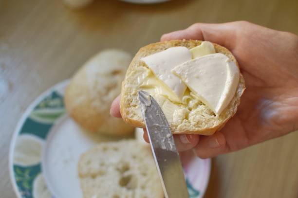 istock Preparing a breakfast, sandwich of white bread, butter and soft cheese, spreading butter 2149953165