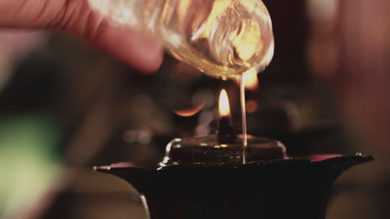 Hand pouring lamp oil to light candles