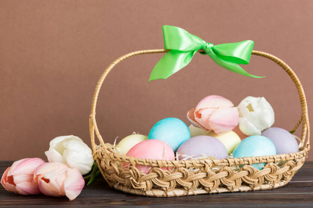 istock Happy Easter composition. Easter eggs in basket on colored table with yellow Tulips. Natural dyed colorful eggs background with copy space 2149956774