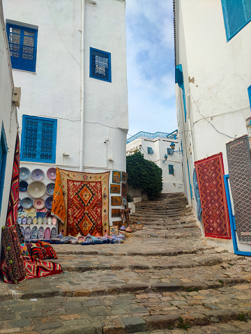 Narrow street in Sidi Bou Said, a famous village with traditional white and blue Tunisian architecture and flowering plants. Tunisia.