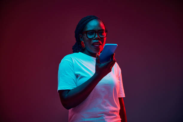 istock Young African-American woman talking on phone in red neon light against gradient studio background. Cellular connection. 2149964288