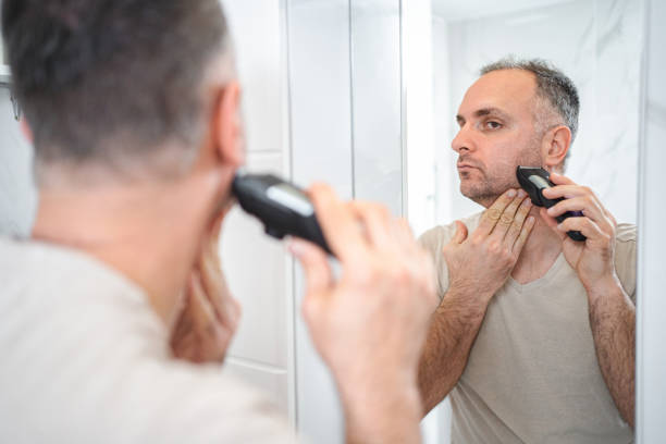 istock Man shaves his beard with a trimmer in the bathroom 2149968696