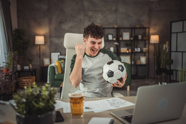 istock A teenager on a study break rests by watching a soccer game on his laptop while sitting at his desk 2149969364