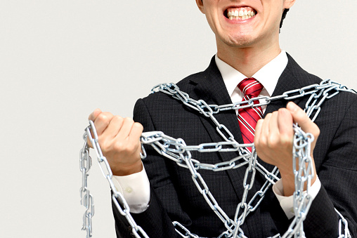 Asian man in a suit tied to a chain