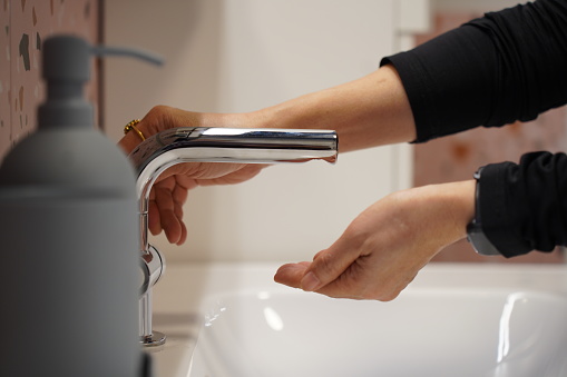 Crop image, Selective focus hands of woman using bottle of liquid soap or shower gel to washing her hands in bathroom,  prevent bacteria and viruses, cleaning of dirty skin for hygiene.