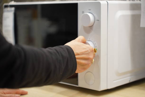 istock woman using microwave oven in her kitchen 2149971340
