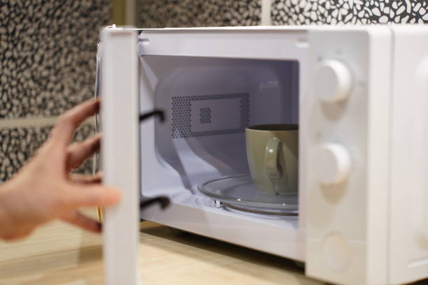 istock woman using microwave oven in her kitchen 2149971346