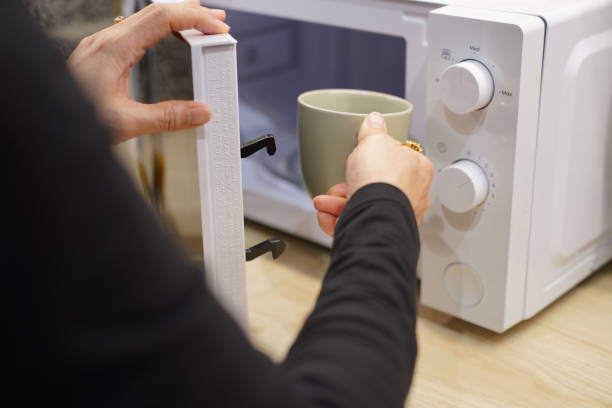 istock woman using microwave oven in her kitchen 2149971357