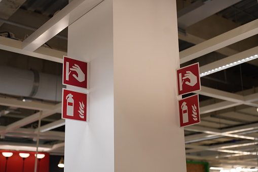 Four Signboard how to use Fire extinguisher in case of emergency on pole over walkway in building