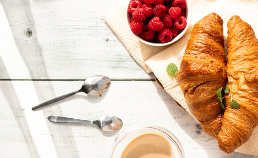 Cup of coffee and croissants and berries. on white wooden. breakfast.