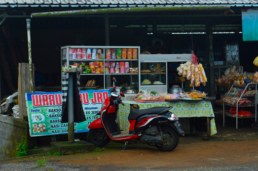 Wanagiri, Buleleng, Bali, Indonesia - Apr 21 2024 : Small Roadside Eatery With Motorcycle Parked Nearby In A Mountainous Village Under Cloudy Weather