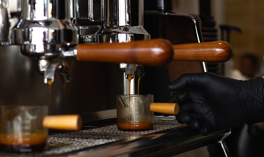 Barista's hands prepares coffee, fresh espresso pours into cup with machine at coffee shop or cafe,The process of making coffee concept.