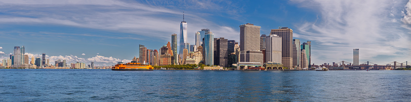 New York City Skyline with Jersey City, NJ, Manhattan Financial District, Battery Park, World Trade Center, Staten Island Ferry, Brooklyn Bridge, Manhattan Bridge, Blue Sky with Clouds and Water of New York Harbor. High Resolution Stitched Panoramic image with 4:1 image aspect ratio. This image was downsized to 50MP. Original image resolution is 113MP or 21,242 x 5,311 px. Canon EOS 6D Full Frame Sensor Camera and Canon EF 85mm f/1.8 USM Prime Lens.