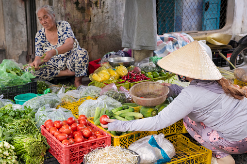 Vietnamese woman selling fruits and vegetables on a local market, Mui Ne, Vietnam