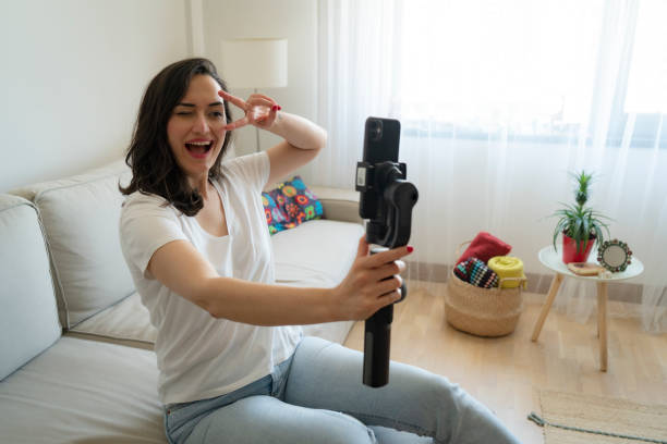 istock Woman using mobile phone recording video live streaming online at home 2149974802