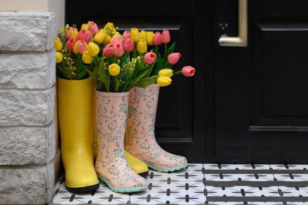 istock Decorative composition at the front door: rubber boots and multi-colored tulips. Design, floral arrangement of spring flowers. Decoration of the entrance to the house. 2149977791