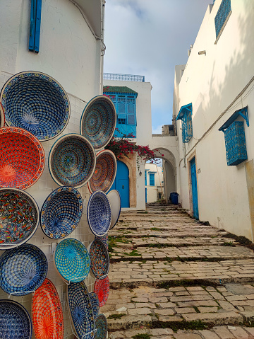 Decorated narrow street in Sidi Bou Said, a famous village with traditional white and blue Tunisian architecture and flowering plants. Tunisia.