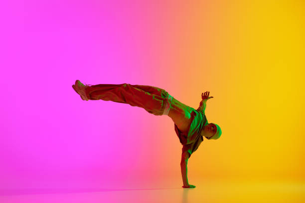 istock Talented break-dancer dancing in motion in neon light against gradient pink-yellow background. 2149981016