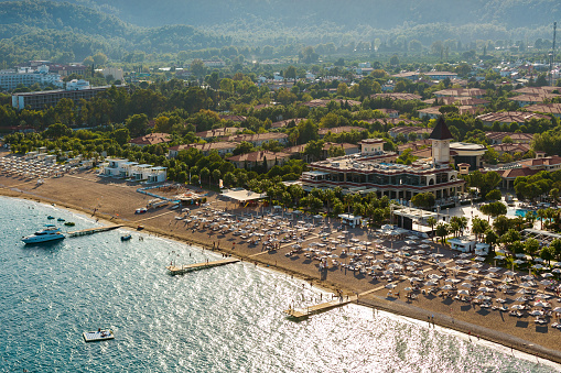 An aerial view of an unrecognizable serene beachfront resort in Turkey, adorned with numerous beach umbrellas
