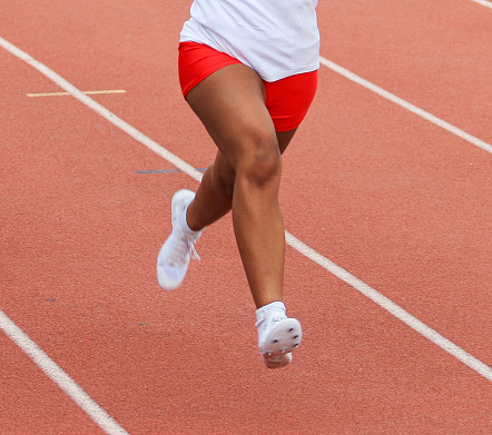 One girl running a race in lane on an outdoor track