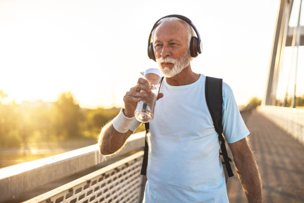 istock Active senior bearded man taking break after hard exercise on the bridge during sunset. Healthy retirement lifestyle. Sports fitness and physical exercises for the elderly. 2149986120