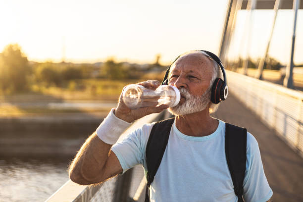 istock Active senior bearded man taking break after hard exercise on the bridge during sunset. Healthy retirement lifestyle. Sports fitness and physical exercises for the elderly. 2149986163