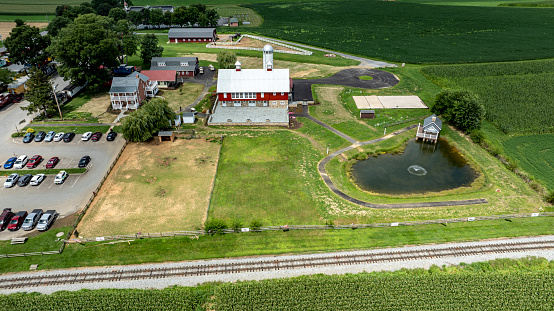 Ronks, Pennsylvania, August 15, 2023 - Captured from above, this photo depicts a rural community center with adjacent parking, a charming pond, and the vast farmland serving as a backdrop.