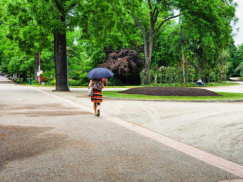 unrecognizable woman holding an umbrella and walking in the Jardin du Grand Rond a public park in Toulouse city in France