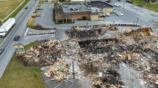 Bird in Hand, Pennsylvania, USA, September 14, 2023 - An Aerial View Of A Devastated Building Amidst Intact Structures With Cars On The Road And Green Fields In The Background Under A Cloudy Sky.