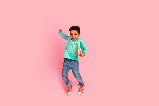 Full body photo of cute little boy jump hold books have fun wear trendy aquamarine clothes isolated on pink color background.
