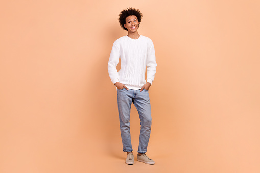 Photo of attractive young man dressed fashionable outfit hands put pockets isolated on beige color background.