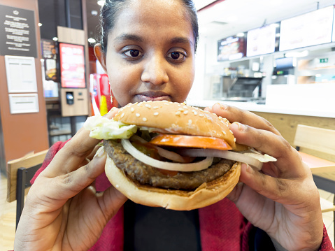 Young woman enjoys hamburger at cafe