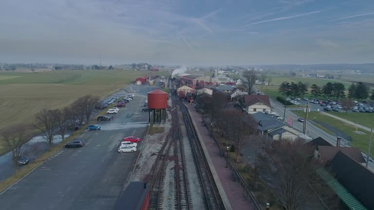 An Aerial View of a Train Station, with a Steam Passenger Train Approaching in the Distance
