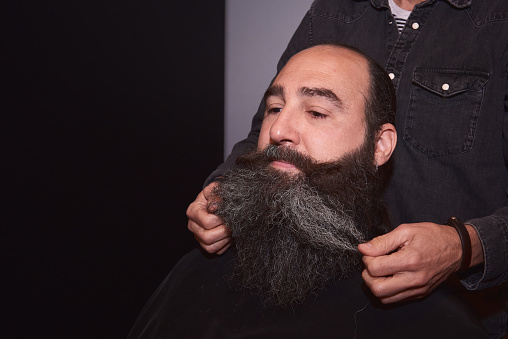 A barber styling a man's beard
