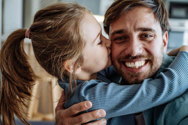 istock Single father having fun with daughter on sofa, hugging and looking at camera 2149990506
